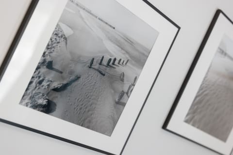 A close-up of three black-and-white framed photographs leaning against a wall. The artwork adds a modern, artistic touch.