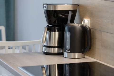 A close-up of a modern coffee machine sitting on a wooden countertop. The machine is black and shiny.