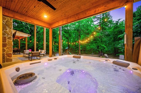 - Spacious covered hot tub surrounded by trees and glowing string lights at dusk - Relax in soothing bubbles while enjoying peaceful woodland scenery and privacy - Lounge area nearby invites you to sip, soak, and unwind outdoors in style  