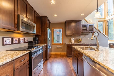 Full-sized kitchen featuring stainless steel appliances, granite countertops, kitchen island, and hardwood floors.