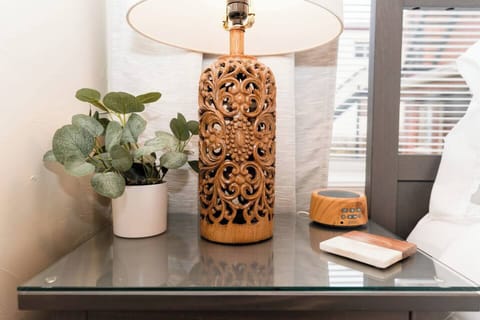 Bedside table with a lamp and a stylish artificial plant accent, adding a touch of charm to the room.