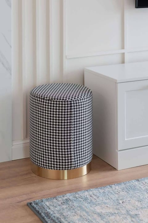 A small, stylish pouf in a neutral tone, adding functionality and comfort to the living space.
