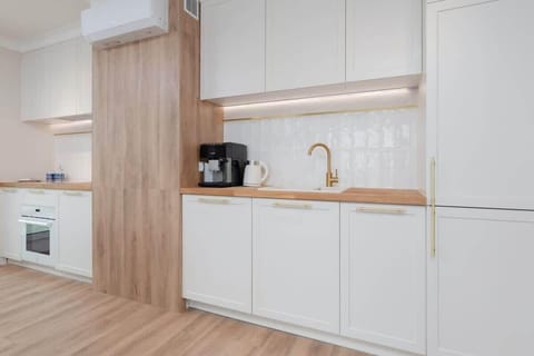 Another view of the kitchen with white cabinets, wooden countertops, and built-in appliances. The modern design ensures ample storage and workspace.