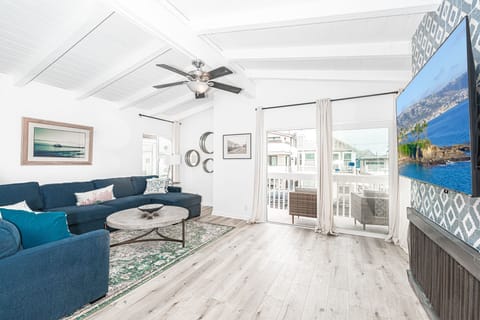 The bright and cheery living area includes a large U-shaped sectional sofa and streaming TV.
                