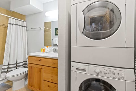 The stacked washer/dryer located in a second bathroom just off of the entry/dining area boasts a single-sink vanity and a shower/tub combo.