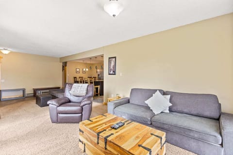 The inviting living area includes two seating areas - one loveseat and two ottomans facing the fireplace and the other a roomy and plush sofa, leather recliner and rustic coffee table near the large, flat-screen TV.