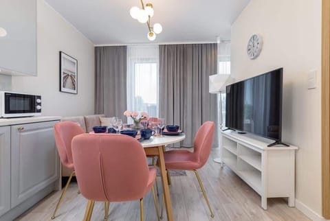 Bright living room featuring pink dining chairs, a sofa, and a small table, with soft natural light.