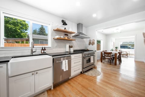 Newly renovated kitchen featuring 6 gas burners, a farmhouse sink, and sleek black quartz countertops