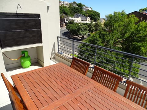 Balcony with six seater dining table and gas BBQ.