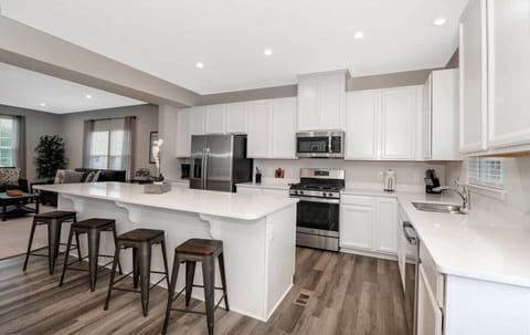 This stunning kitchen is a chef's dream, featuring top-of-the-line stainless steel appliances, sleek cabinetry, and beautiful countertops. The large center island offers ample space for meal prep and dining, while the open layout makes entertaining e