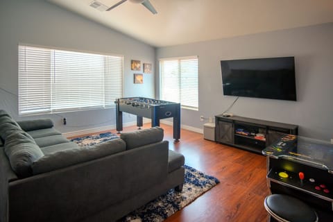 Game room with comfy sectional, large Smart TV, foosball and video console.