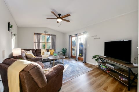 - Bright living room with large windows and natural light   - Cozy sectional seating with TV for family entertainment   - Easy access to outdoor deck with peaceful water views