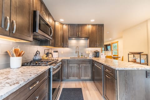 Full size kitchen with stainless steel appliances, granite countertops and hardwood flooring.