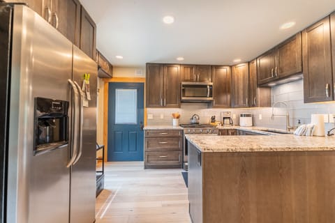 Full size kitchen with stainless steel appliances, granite countertops and hardwood flooring.
