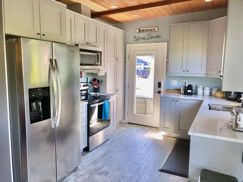 Kitchen with full size fridge, stove and dishwasher. Opens to sunny patio