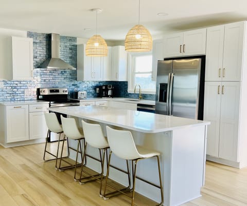 Cooking is a pleasure in this bright, beautiful and well-stocked kitchen that includes a large island, plenty of cabinet space, a pantry for your groceries, and beautiful wave-like tiles.