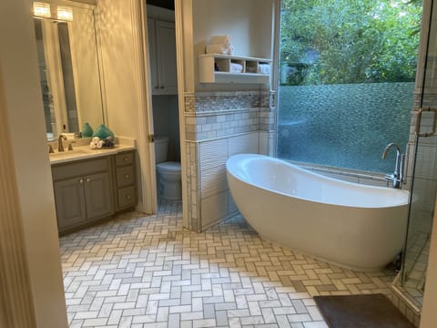 Primary ensuite bathroom with walk-in shower, tub, double sinks and garden views