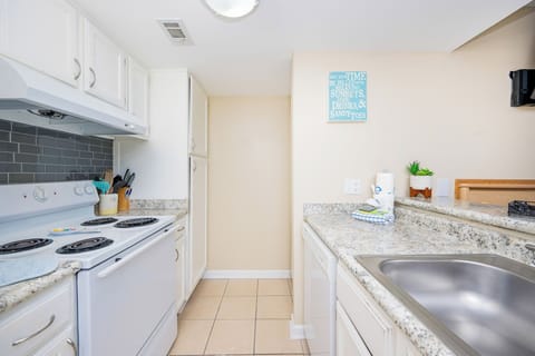 The kitchen features white appliances, granite countertops, and a cheerful decor, perfect for preparing meals