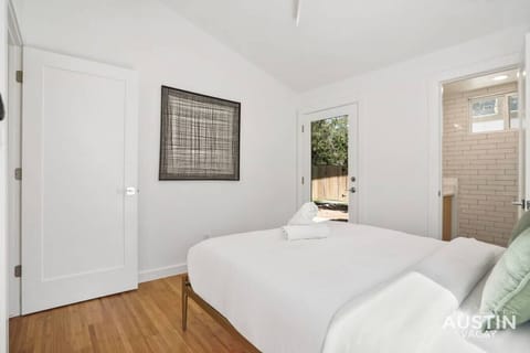 Queen bedroom with luxury hotel linens, bathroom, and work desk
