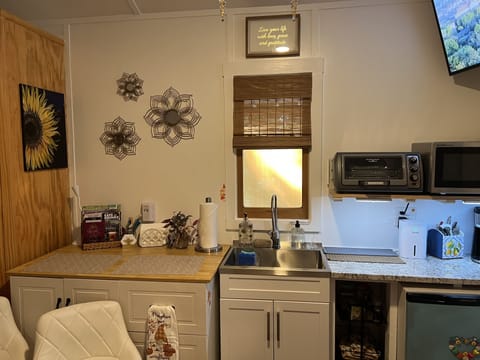 Kitchen sink, countertop/storage cabinet with glasses, mugs, plates, bowls, etc.
