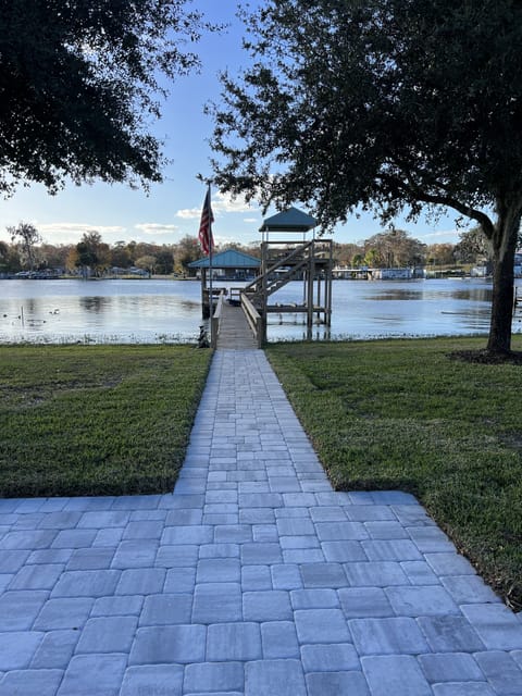 Paver walkway to dock with covered lift, upper deck, and additional boat parking