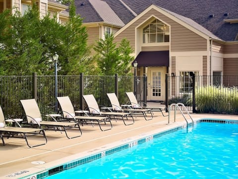 Lounge poolside under blue skies and warm afternoon sun.
