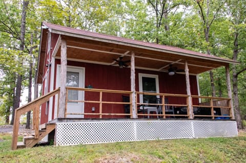 - Cozy red cabin nestled in peaceful forest views   - Relax on the covered porch with rustic wood beams   - Perfect nature escape near hiking and outdoor fun