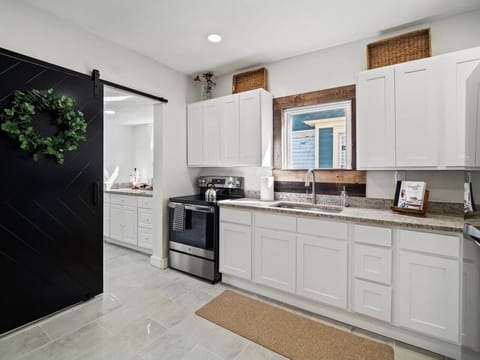 Kitchen with white cabinets and stainless steel stove - Granite counters and wood accents highlight the space - Functional layout ready for cooking and dining