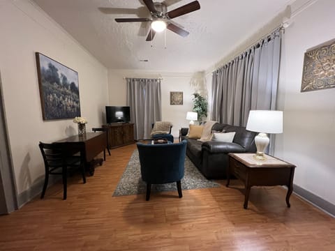 Living room with couch, chairs, TV and dining table.