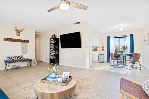 Open floor plan living room and dining room with a 65" TV and tile floors.