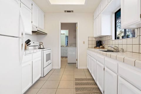 The white tiled kitchen with a kettle and coffee maker.