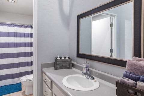 A Full Restroom with a hair dryer, shampoo, body wash, towels, toilet paper and conditioner