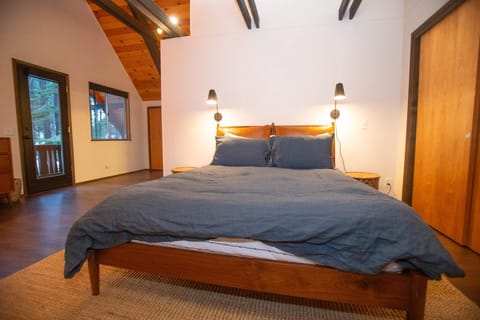 The first upstairs bedroom is a stylish and spacious room with soaring vaulted ceilings, a queen-size bed, and access to a private balcony.