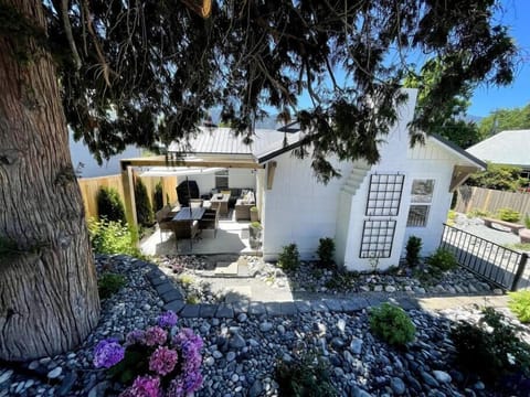 Front of the house with side patio complete with dining table, and sectional with gas fire pit.