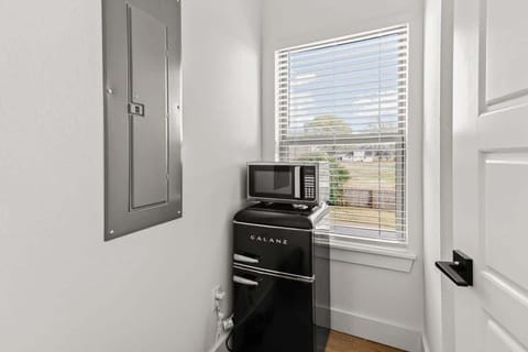Snack time made easy with a retro mini‑fridge and microwave positioned by a sunny window.