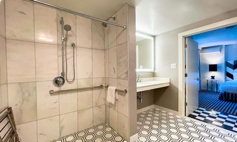 Bathroom with a shower. The essential kit and towels are provided! It features ADA mobility amenities including grab bar attached accessible seating, roll-in shower, lowered vanity in bathroom, and lowered shelf in closet.