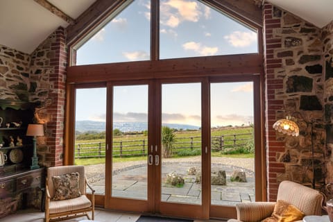 Huge cathedral windows in living space with views over garden, pasture and sea.