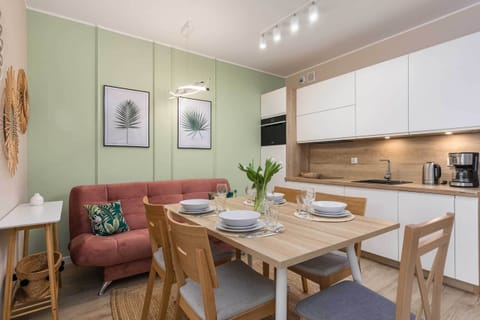 A dining area with a pink upholstered bench and a light wood table set for a meal.
