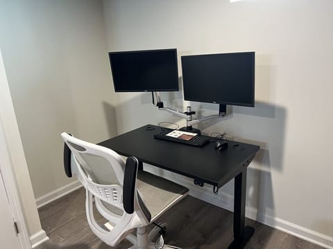 Gaming corner with standing desk, dual monitors with docks, keyboard, mouse, and comfortable office chair