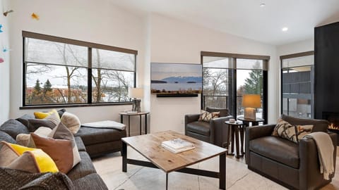 The grand master living room features a gas fireplace, rivew views, a balcony, open concept kitchen, living room, and dining area.