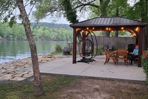 Relax lakeside under the charming gazebo with string lights and comfortable seating, perfect for evening gatherings.