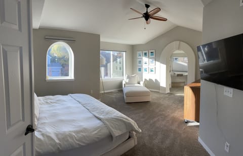 master suite with lounge chair and TV mounted facing bed