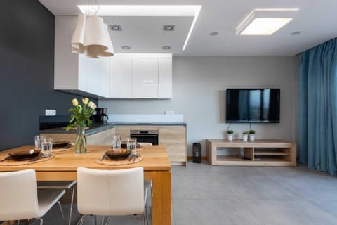 A cozy living room with a gray couch and blue curtains, featuring a wooden coffee table and a view of a balcony, letting in plenty of natural light.