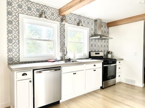 Kitchen is equipped with pots, pans, cooking utensils, dish towels & pot holders