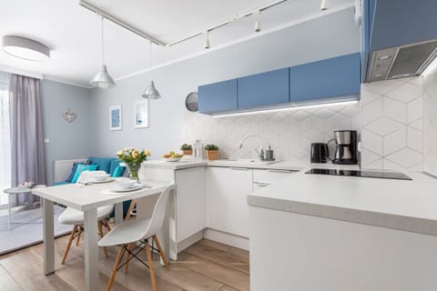 A beautiful kitchen with a blue and white color scheme, featuring modern cabinets, a large countertop, and decorative plants for a fresh look.