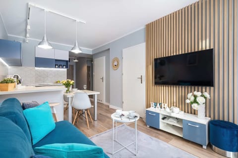 A modern living room decorated in shades of blue and white, featuring a cozy blue sofa with matching pillows, a minimalist coffee table, and bright natural lighting from large windows.