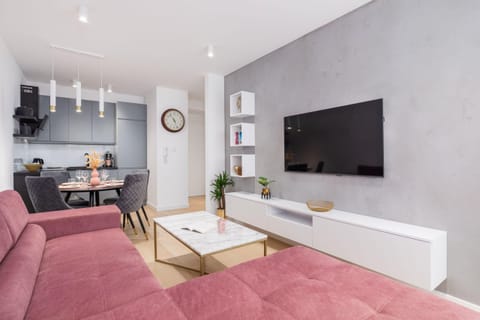 A cozy living area with a mounted TV, shelves, and a bright atmosphere.
