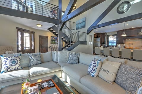 Living area with plush seating, uniquely crafted beams, & statement staircase