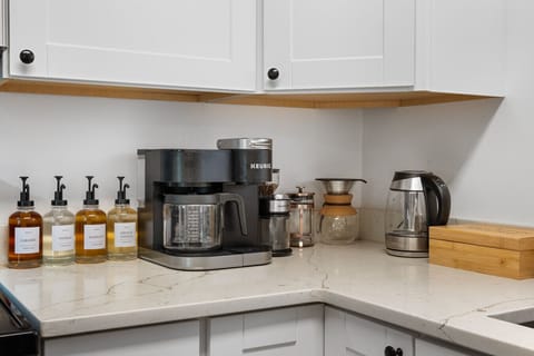 Deluxe coffee bar featuring Keurig, French press, pour-over, and flavored syrups for coffee lovers.