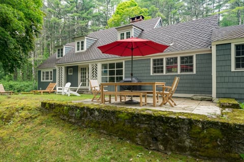 Spacious deck features an outdoor dining table and seating that looks toward the trees.